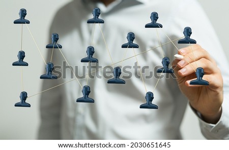A hand touching 3d rendered network of profile icons with a pen