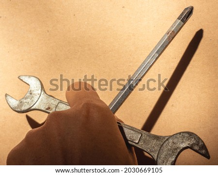 selective focus of hands holding wrench and screwdriver on brown color. copy space for text. Can be used for Labor Day event background.