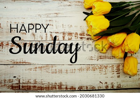 Happy Sunday text and Bouquet of yellow tulips on white wooden background