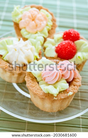 Delicious sweet sandbag baskets with cream on a green bamboo tablecloth.