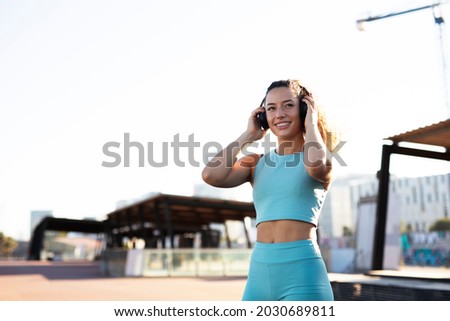 Young sporty woman with headphones. Beautiful woman listening the music while preparing for the training	