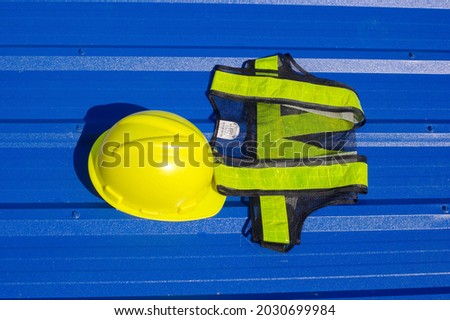 Yellow safety helmet  and safety reflective vest  on blue background., metal sheet background