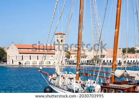 Mandraki Port with yacht masts in front and Evangelismos Church on the background