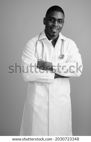 Studio shot of young handsome African man doctor against gray background in black and white