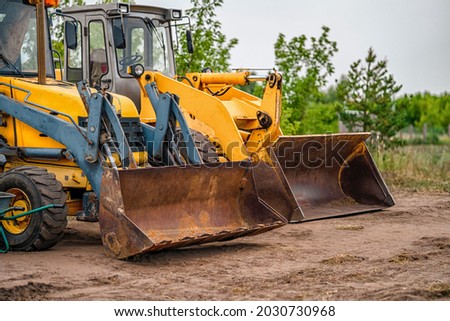 Tractors excavators are standing in a field in the village