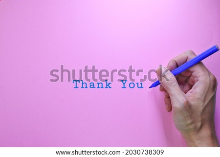 a man's hand writes thank you, with a blue marker on purple paper. Thank You text words typography, Business Concept, Motivational concept. Marketing and Communications Concept. purple Background