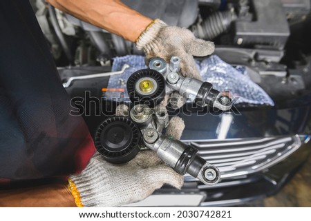 Close-up of Drive Belt Automatic Tensioner and Pulley on Auto mechanic hands. Royalty-Free Stock Photo #2030742821