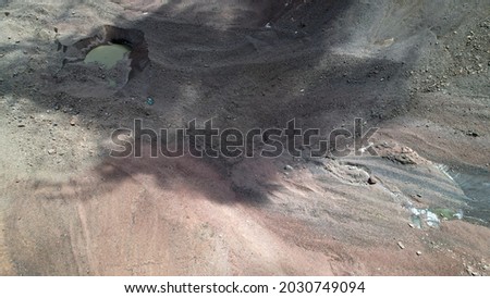 A moraine lake among a glacier covered with rocks. The glacier is melting. Shadows from clouds. View of the lake from above from the throne. A lake among high snowy mountains. Kazakhstan, Almaty