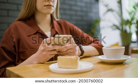 Woman taking food pictures on smartphone in restaurant, social media content