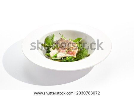 Panfried Fish with broccoli and green spinach. Healthy roasted cod with asparagus espuma. Fried Fish on white restaurant plate isolated on white background