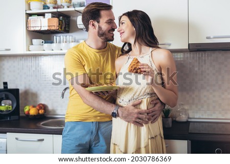 Pregnant woman with husband in the kitchen having fun.