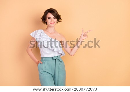 Photo of young attractive girl happy positive smile point finger empty space ads advice isolated over beige color background
