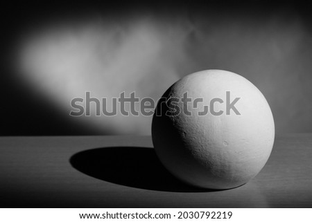 a black-and-white plaster ball with its own and falling shadow, penumbra, reflex, chiaroscuro. Royalty-Free Stock Photo #2030792219