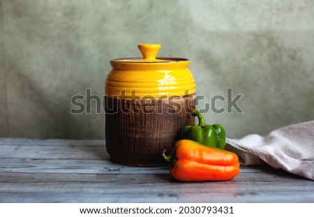 yellow clay barrel for food storage and fresh green and orange sweet peppers, harvest, autumn kitchen, stocks for the winter