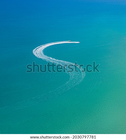 Watersports at the beach. Speedboat and wave slider leaving zigzag trail on water, view from above Royalty-Free Stock Photo #2030797781