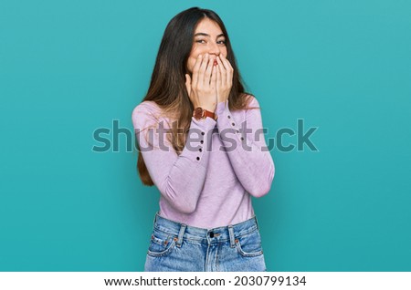 Young beautiful teen girl wearing turtleneck sweater laughing and embarrassed giggle covering mouth with hands, gossip and scandal concept 