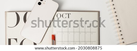 Minimalist and clean Female workspace smart phone , calendar and red lipstick. October 