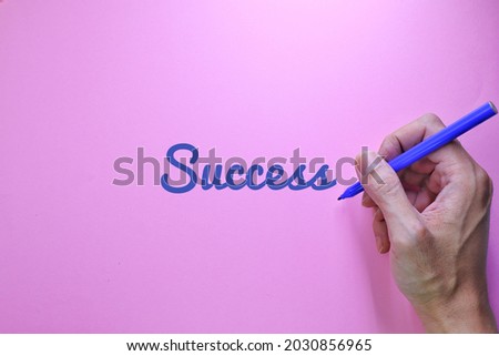 Success text words typography, Business Concept, Motivational concept. Marketing and Communications Concept. A man's hand writes Success, High angle view. Pink Background
