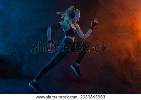 Sprinter run. Strong athletic woman running on black background wearing in the sportswear. Fitness and sport motivation. Runner concept. Royalty-Free Stock Photo #2030865983