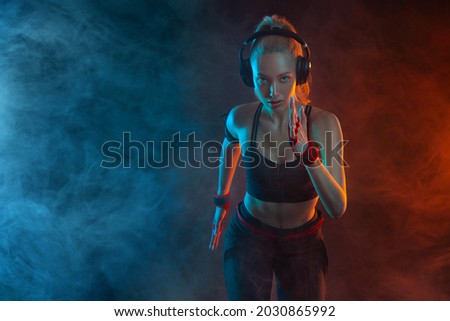 Sprinter run. Strong athletic woman running on black background wearing in the sportswear. Fitness and sport motivation. Runner concept. Royalty-Free Stock Photo #2030865992