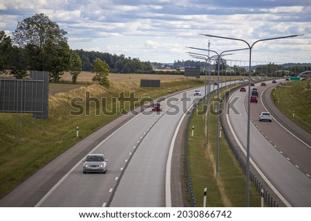 Beautiful view from above on highway road with several cars. Green side fields and blue sky background. Sweden.