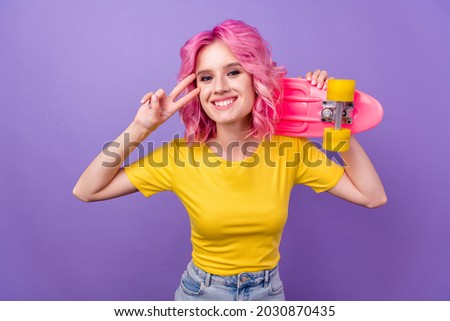 Photo of young cheerful girl happy positive smile show peace cool v-sign skateboard isolated over purple color background