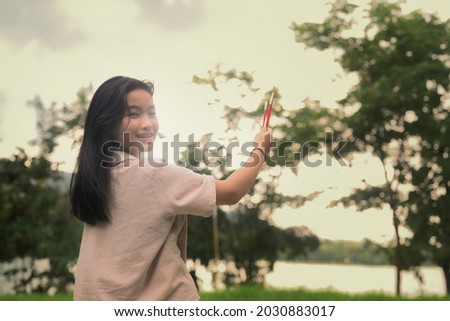 Asian girl holding painting brush and smiling to camera while standing in the park.