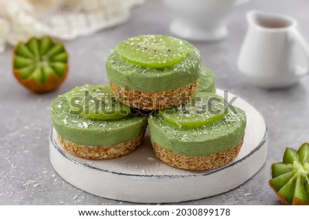 Raw vegan dairy and gluten free avocado dessert. Mini avocado cheesecakes on a nut coconut and date crust and topped with kiwi slices. Royalty-Free Stock Photo #2030899178
