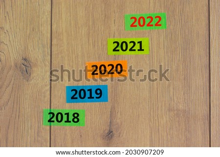 2022 happy new year symbol. Colored paper with number '2022'. Colored papers with numbers '2018, 2019, 2020, 2021'. Beautiful wooden background. Copy space. Business, 2022 happy new year concept.