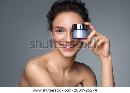 Beautiful woman with jar of moisturizer cream. Photo of woman with perfect skin on gray background. Beauty and Skin care concept