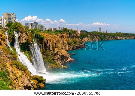 Lower Düden Falls drop off a rocky cliff falling from about 40 m into the Mediterranean Sea in amazing water clouds. Tourism and travel destination photo in Antalya, Turkey. Royalty-Free Stock Photo #2030955986
