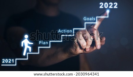 Businessman pointing to the growing plan of successful business in 2022 year and a figure climbs the ladder of success. Year 2022 plan, action and goals.  Royalty-Free Stock Photo #2030964341