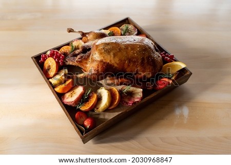 Roasted duck with assorted fruits on a wooden tray in the rays of the sun