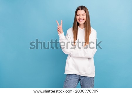 Photo portrait girl smiling showing v-sign gesture in white clothes isolated pastel blue color background