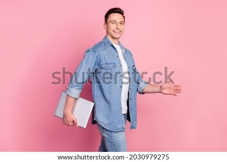 Photo of young smiling handsome smart businessman go walk with wireless netbook isolated on pink color background
