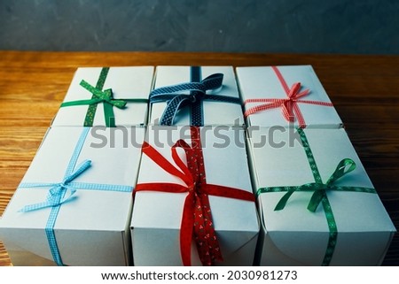 Close up of gifts stack. White boxes with ribbons on wooden table. Composition for birthday or new year. Preparing for Christmas. Festive still life.