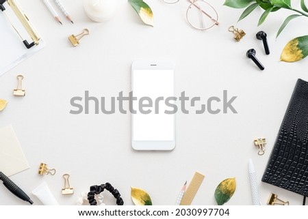 White office desk table with smartphone mockup, offices supplies, fall leaves. Feminine home workspace. Top view with copy space. Flat lay. 