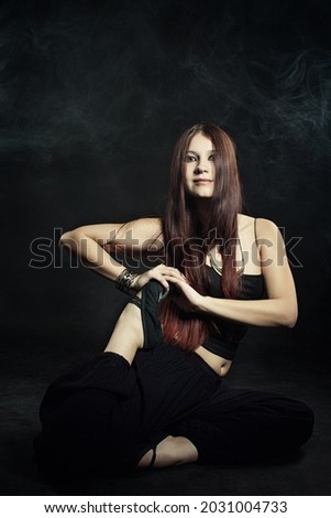 Young woman in yoga position over dark background