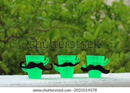 Small plastic tequila glasses wearing a moustache. Mexican concept.