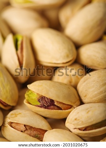Many whole and open pistachio nuts with a green heart. Macro photography. High angle view. Confectionery, bakery, pub. Poster, banner, advertisement.