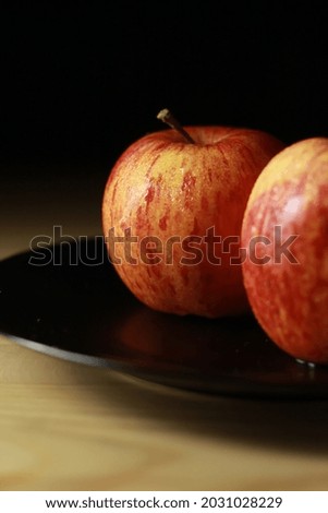 red fresh apple with black plate and brown table