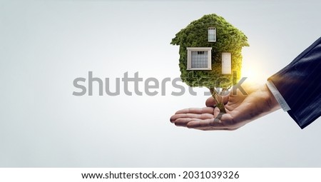 Hand holding green house . Mixed media . Mixed media