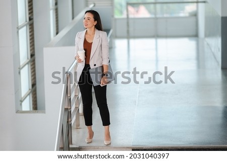 Portrait Of A middle-aged Asian woman Successful Business Woman Holding laptop and White take away coffee Of Hot Drink In Hand at office