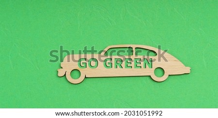 Ecology and transportation concept. On a green background, a wooden car with the inscription - GO GREEN