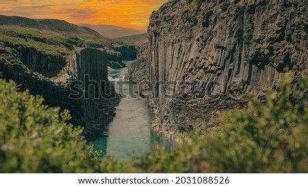 Overview of Studlagil canyon in Iceland, picturesque valley with basalt columns standing high on a warm summer day. Shot taken trough grass Royalty-Free Stock Photo #2031088526
