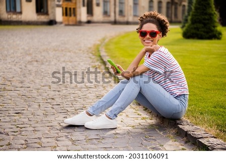 Full length profile side photo of young attractive african woman happy positive smile use cellphone wear glasses outdoors