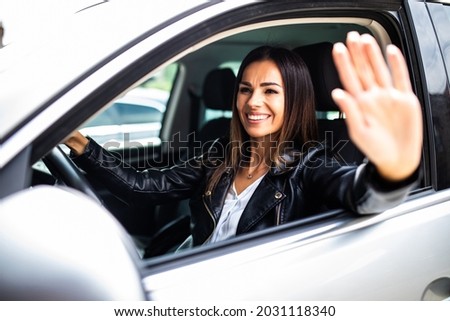 Young woman greeting with hand from car. Cheerful caucasian girl welcome somebody sitting in automobile Royalty-Free Stock Photo #2031118340