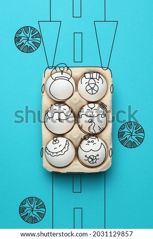 Funny chicken eggs in cardboard car on color background, top view