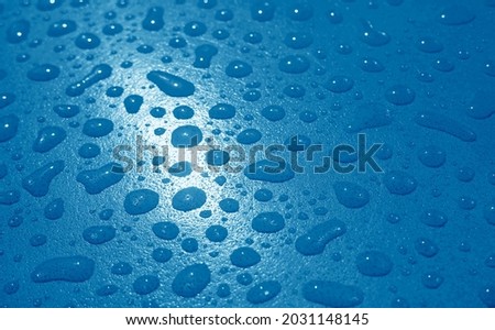Closeup of cobalt blue colored water droplets on the garden table after the rain