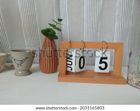 Flower pot and wooden Jun 5 calendar on white table floor for design or background, stock photo
